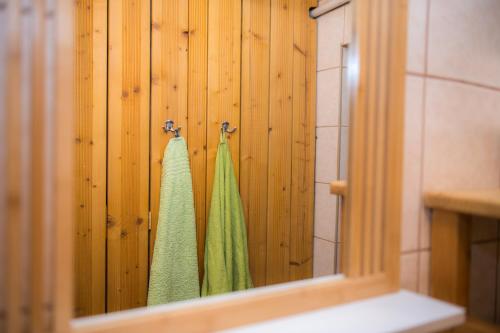 a bathroom with green towels hanging on a wooden wall at Katschwaldhütte in Sankt Wolfgang