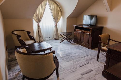 a living room with a table and chairs and a television at Palace Inn in Jíloviště