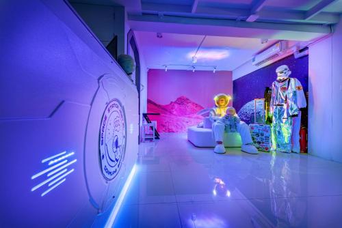 a room with two mannequins sitting on a couch next to a car at Space Station Hostel in Ban Don Muang