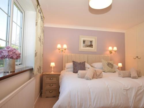 um quarto com uma cama com lençóis brancos e almofadas em 3 Bed in Fakenham 56661 em Whissonsett