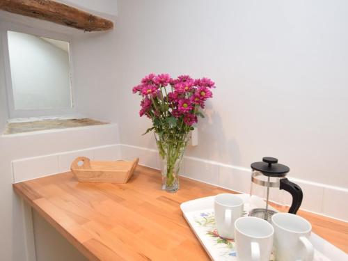 a vase of flowers sitting on a table with cups at 3 Bed in Bridport 57688 in Mosterton