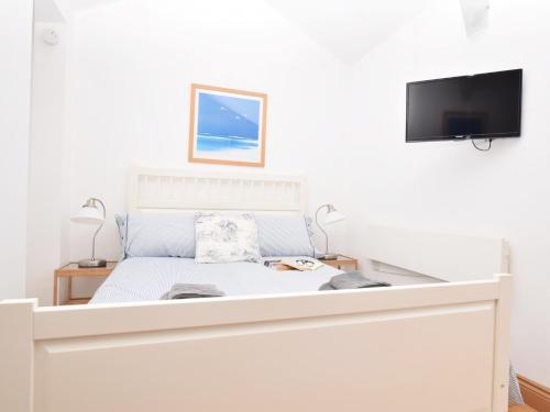 a white bedroom with a bed with a tv on the wall at 1 Bed in Nr Bamburgh CN002 in Lucker