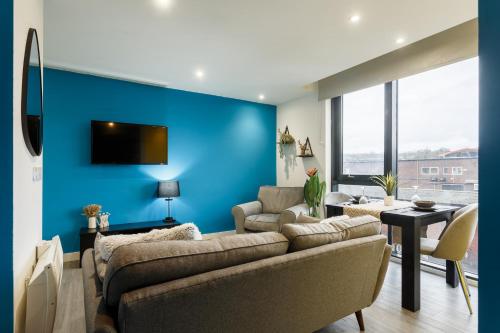 a living room with a couch and a blue wall at Brand New Studio Apartment in Sheffield in Sheffield