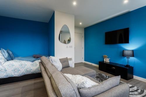 a bedroom with blue walls and a couch and a bed at Cozy Studio Apartment in Sheffield in Sheffield