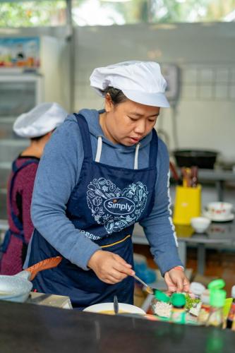 a woman standing in a kitchen preparing food at LuangPrabang Center Hotel in Luang Prabang