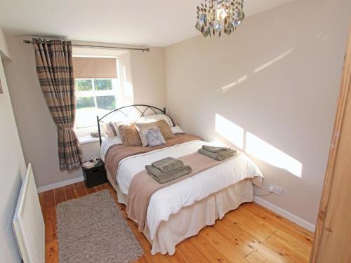 a bedroom with a bed and a window and a chandelier at 2 Bed in Nr Amble CN049 in Acklington