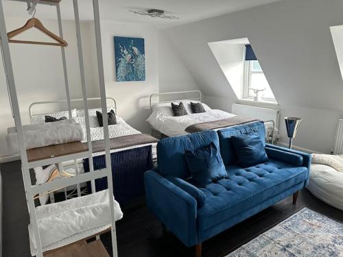 Dartford Town 3 Bed by Harlington في Kent: غرفة معيشة مع أريكة زرقاء وسريرين