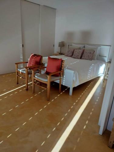 a bedroom with a bed with two chairs and a table at Quinta do Pinhô - The Poolhouse in Salzedas