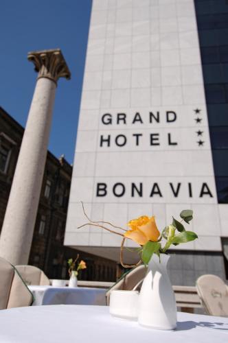 a table with a vase with a flower in front of a building at Grand Hotel Bonavia in Rijeka