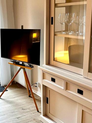 a room with a tv and wine glasses in a cabinet at Gemütliche Ferienwohnung in Uelzen mit eigenem Garten in Uelzen