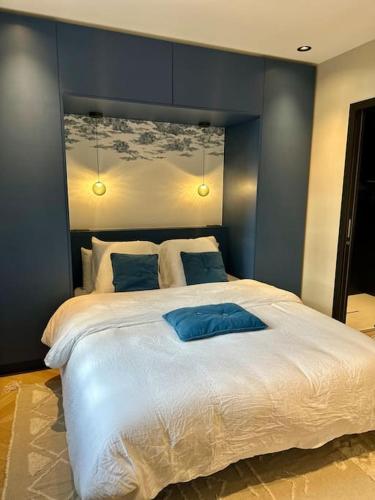a bedroom with a large white bed with blue walls at L'Atelier Panama in Coutiches