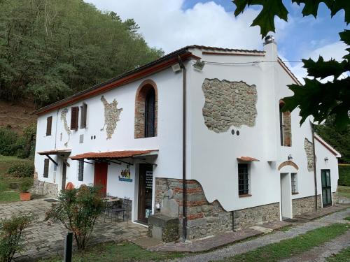 eine alte weiße Kirche mit einem Steingebäude in der Unterkunft Podere Campofossato in Pistoia