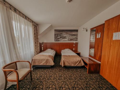 a hotel room with two beds and a chair at Hotel Azyl in Kąty Wrocławskie