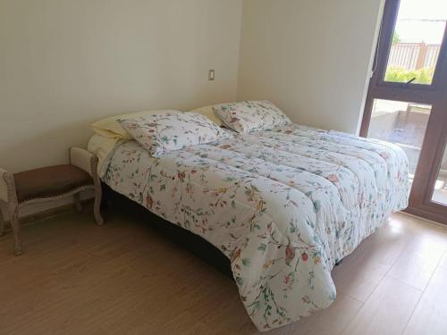 a bed with a comforter and a chair in a bedroom at Departamento familiar Villarrica in Villarrica