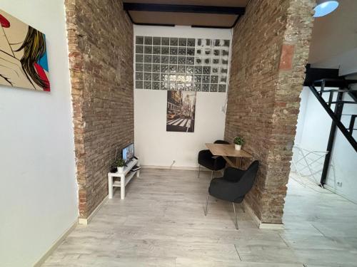 Habitación con pared de ladrillo, mesa y sillas. en Estudio para parejas en Barcelona