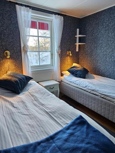 1 dormitorio con 2 camas y ventana en Toppstugan, en Åkerö