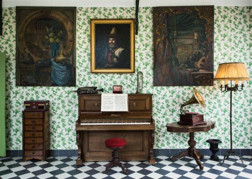 a room with a piano and a desk and paintings at Demeure Castel Brando Hôtel & Spa in Erbalunga