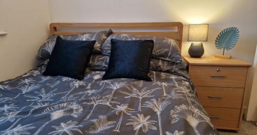 a bed with a blue comforter and two pillows at Business & Leisure City Centre 2 Bed En-suite Apartment with free parking and Netflix in Coventry