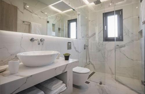 a white bathroom with a sink and a shower at Villa Anelle in Karavadhos