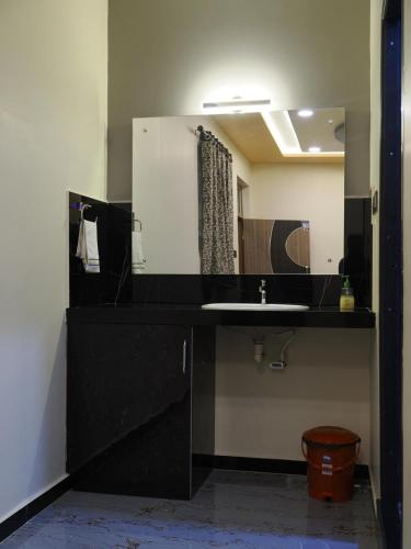 a bathroom with a black sink and a mirror at Coconut Homestay Hampi in Hampi