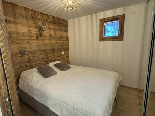 - une chambre avec un lit et un mur en bois dans l'établissement Les Gets: Appartement cosy, garage privé, Wi-Fi, linge inclus - FR-1-671-256, aux Gets