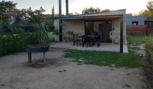 una casa con mesa, sillas y parrilla en ALMA Posada en Almafuerte