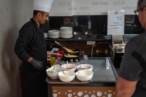 a man standing in a kitchen preparing food at My Hotel by Trend in Aqaba