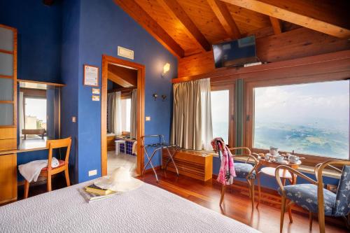 1 dormitorio con paredes azules, mesa y ventana grande en Hotel Cesare, en San Marino