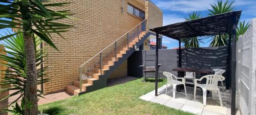 a patio with a table and chairs and a staircase at Kleinmond Panorama Holidays in Kleinmond