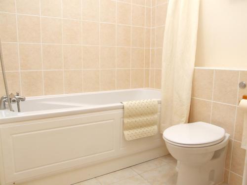 een badkamer met een wit bad en een toilet bij Mas Des Sables Seaside Cottages in Grandes Rocques