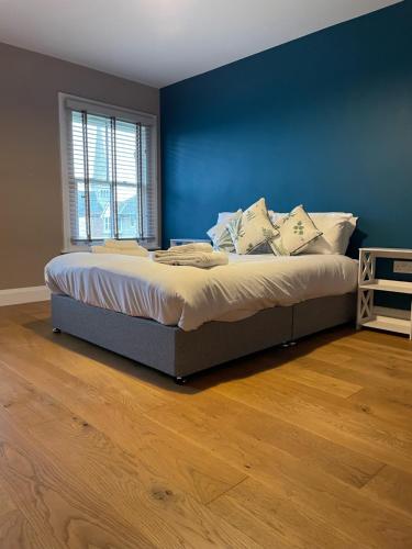 a bed in a bedroom with a blue wall at Two Bedroom Duplex Apartment The Priory in St. Ives