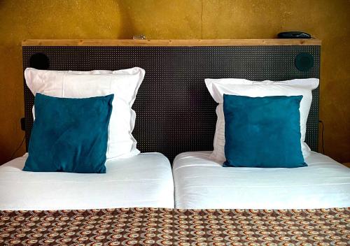 two beds with blue and white pillows on them at Hôtel La Nouvelle République & Hammam in Paris