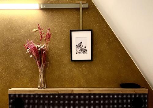 a vase of flowers on a table with a picture at Hôtel La Nouvelle République & Hammam in Paris