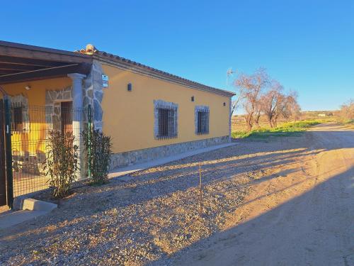 a yellow building with a fence next to a road at Casa Rural La Veguilla in Argés