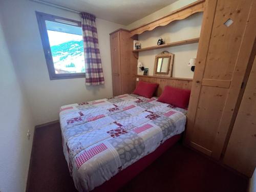 sypialnia z łóżkiem z czerwonymi poduszkami i oknem w obiekcie Appartement Lanslebourg-Mont-Cenis, 2 pièces, 4 personnes - FR-1-508-286 w mieście Lanslebourg-Mont-Cenis
