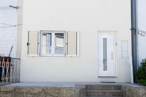 a white house with two windows and stairs at Casa da fonte de baixo in Barcelos