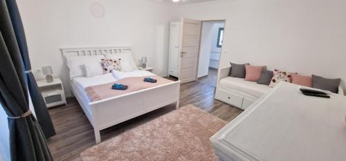 a white bedroom with a bed and a couch at Kékkút Cottage in Nagyvisnyó