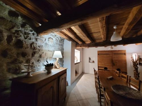 a dining room with a table and a stone wall at Lerefugedetiti in Buissard