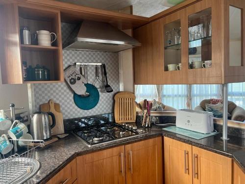 a kitchen with wooden cabinets and a stove top oven at Cuddfan in Llanrhystyd