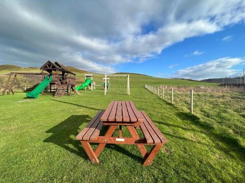 uma mesa de piquenique num campo com parque infantil em Cuddfan em Llanrhystyd