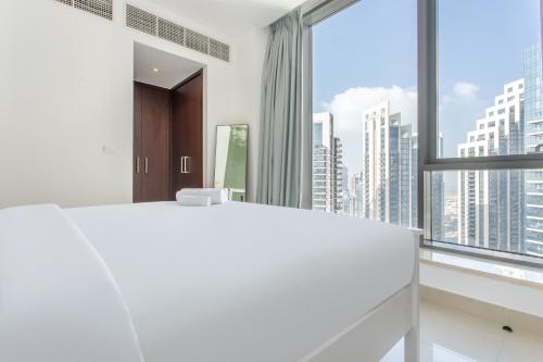 1 dormitorio con 1 cama blanca grande y ventana grande en WeHost - Modern 1BR Close to Burj Khalifa and Dubai Mall, en Dubái