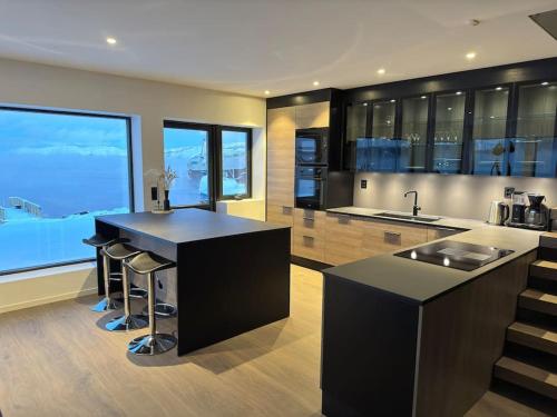 a kitchen with a black counter and a large window at Arctic Sea Breeze in Kirkenes