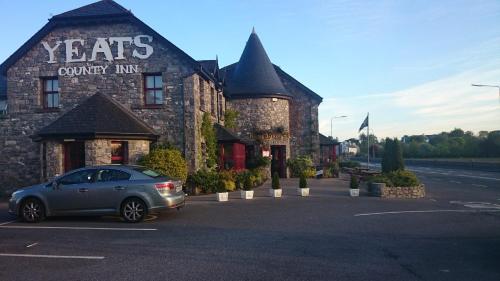 een auto geparkeerd op een parkeerplaats voor een gebouw bij The Yeats County Inn Hotel in Tobercurry