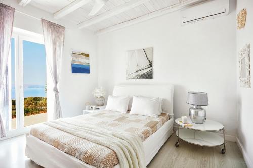 a white bedroom with a bed and a window at Luxury villa in Kechria in Kechria