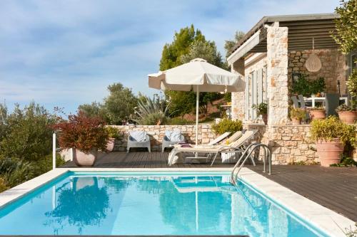 a swimming pool with an umbrella and a house at Luxury villa in Kechria in Kechria