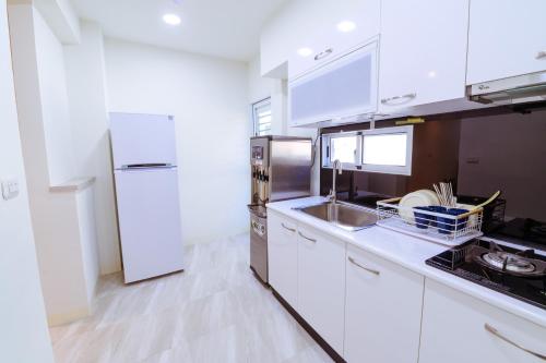 a kitchen with white cabinets and a stainless steel refrigerator at Itaewon in Tainan