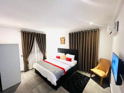 een hotelkamer met een bed en een stoel bij Karjel Homes Apartments in Sunyani