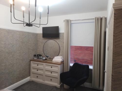 a room with a chair and a mirror and a dresser at Linroy Guest House in Skegness