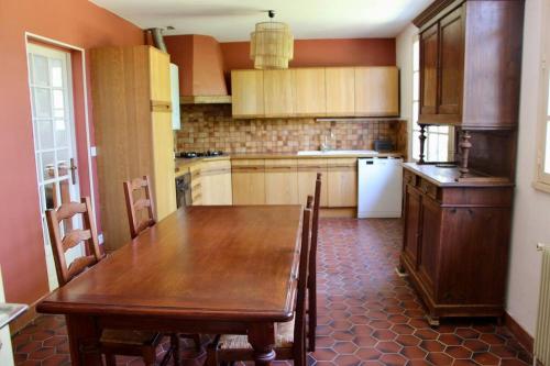 a kitchen with a wooden table with chairs and a refrigerator at Maison de Campagne 
