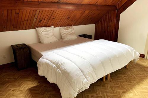 a bedroom with a large white bed with wooden ceilings at Maison de Campagne 